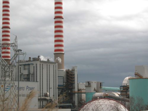 Industrieanlage mit zwei rot-weiss gestreiften Kaminen und Kuppelbau unter grauem Himmel