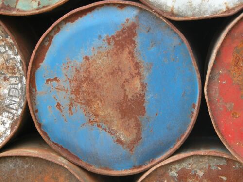 Blauer Fassdeckel mit grossem, rostbraunem Fleck in der Mitte zwischen anderen Fässern, Fotografie aus der Serie «Alltägliche Fundstücke II»