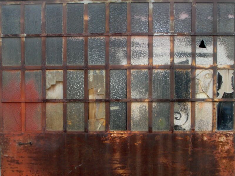 Altes Industriefenster mit Riffelglas, einem Loch und Graffitiresten über rostiger Brüstung, Fotografie aus der Serie «Alltägliche Fundstücke II»