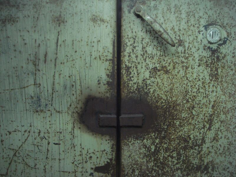 Blassgrüne Doppeltür aus Metall mit Rostsprenkeln, Griff und Schloss, Fotografie aus der Serie «Alltägliche Fundstücke II»