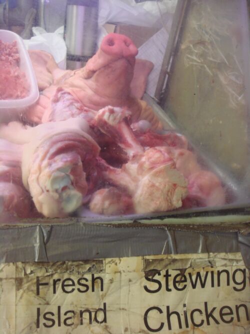 Schweinekopf und Fleischstücke in einer Metzgereiauslage über dem Schild «Fresh Island Stewing Chicken», Fotografie aus der Serie «Honolulu»